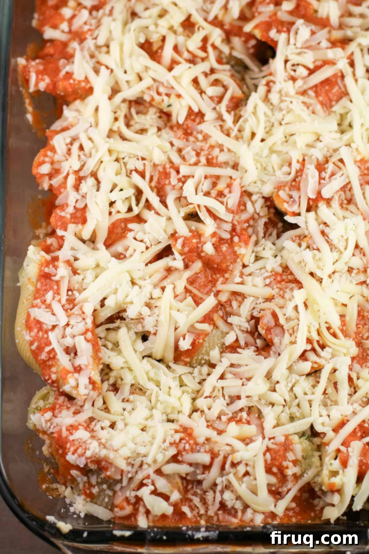 Zesty Cajun Shrimp and Crab Stuffed Shells with Creamy Vodka Sauce 8 A baking dish filled with assembled Cajun Shrimp and Crab Stuffed Shells, covered in vodka sauce and cheese, ready for baking.