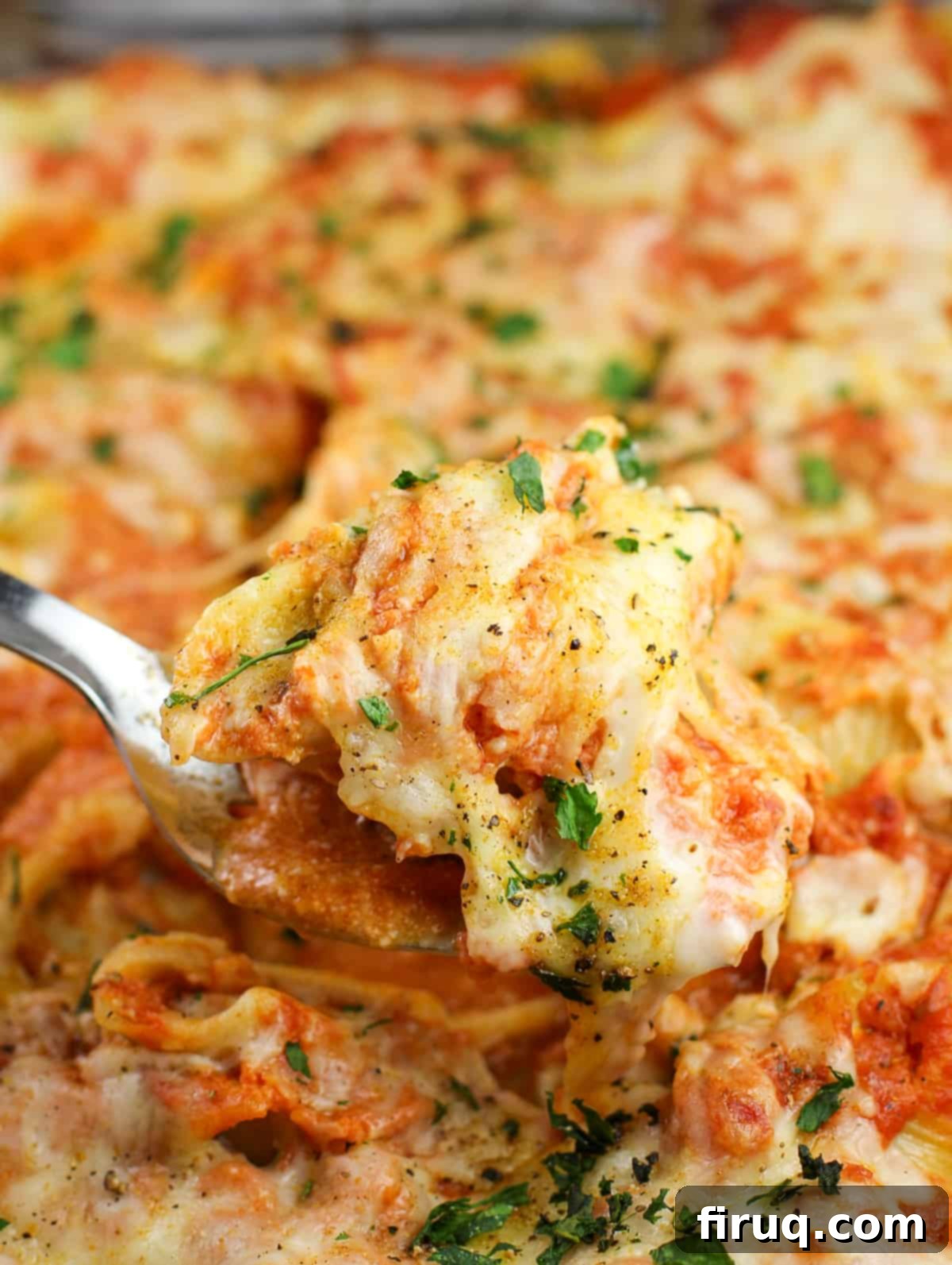 Zesty Cajun Shrimp and Crab Stuffed Shells with Creamy Vodka Sauce 9 A spatula lifting a single, perfectly baked Cajun Shrimp and Crab Stuffed Shell from a warm casserole dish, highlighting the texture and richness.