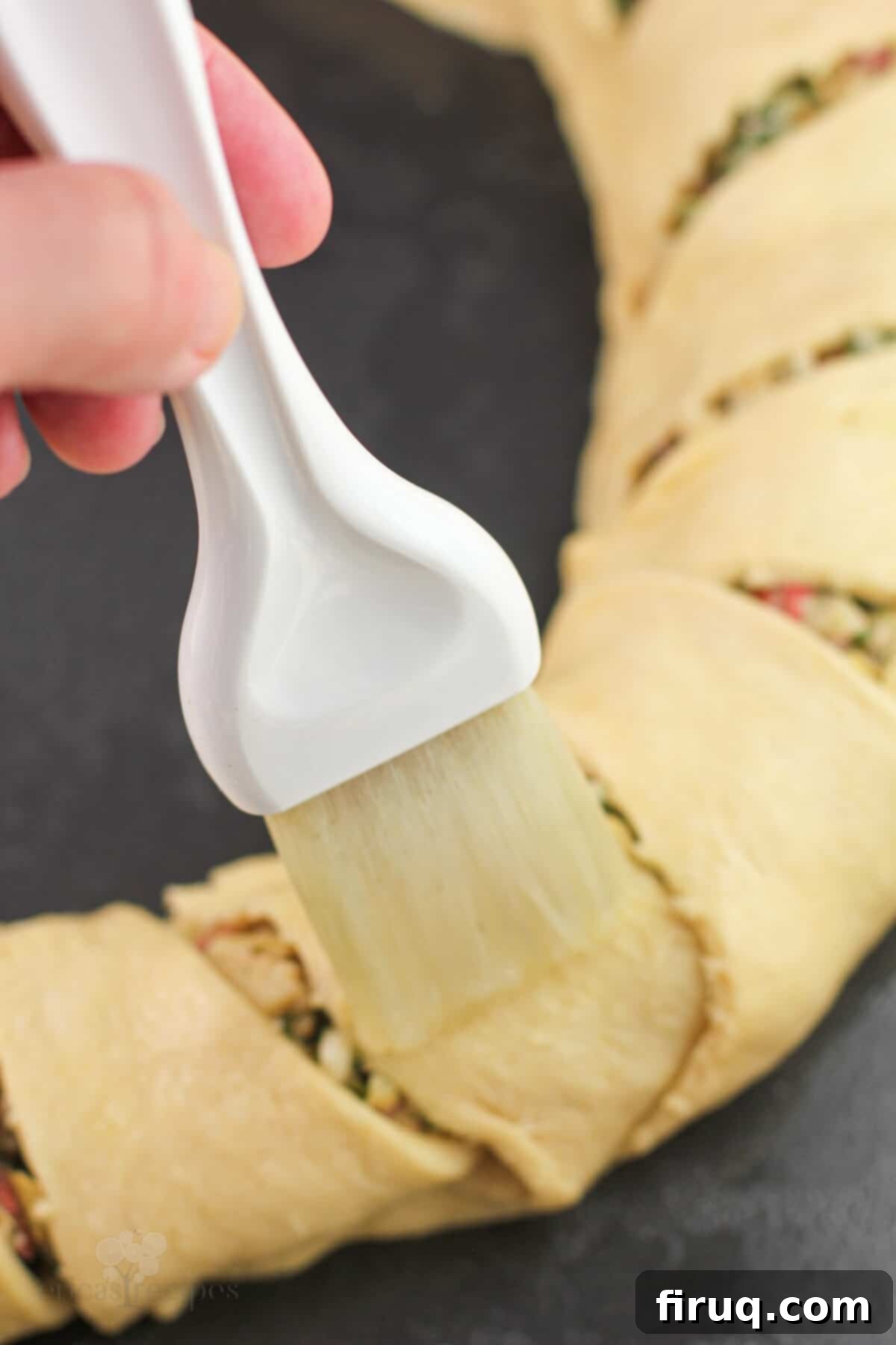 Mediterranean Crescent Wreath 8 A pastry brush applying egg white to the raw Mediterranean crescent ring dough before baking